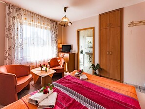 Ein Hotelzimmer mit Bett, Sofa, Fernseher, Schreibtisch und Kleiderschrank.