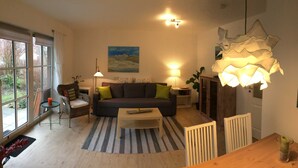 A living room with a sofa, a coffee table, a lamp, and a painting on the wall. - Wolke 7 Vacation Rental - - Wolke 7 Vacation Rental (Brodersby)