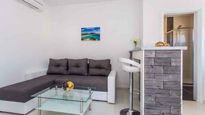 Ein modernes Wohnzimmer mit einem grauen Ecksofa, einem Glastisch und einer Wand mit Steinverkleidung.