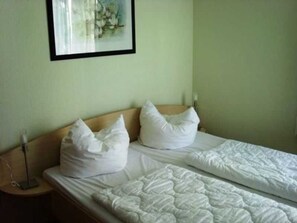 Ein Hotelzimmer mit einem Bett, Kissen, einem Nachttisch und einem Wandbild.