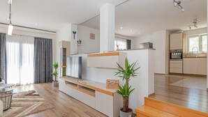 A modern living room with a flat-screen TV, wooden shelving, and potted plants. - Amazing home in Zaton (Zaton)