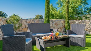 An outdoor seating area with wicker furniture, a stone wall, and a grassy lawn. - Amazing home in Zaton (Zaton)