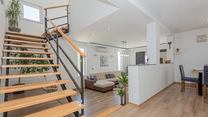 A modern interior with a wooden staircase, a living area with a sofa, and a dining area with chairs. - Amazing home in Zaton (Zaton)