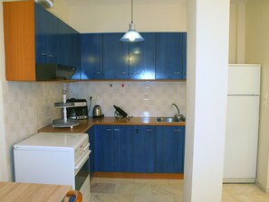 A kitchen with blue cabinets, a white refrigerator, a coffee maker, and a sink.