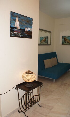 A room with a bed, a wall-mounted lamp, and maritime-themed artwork.