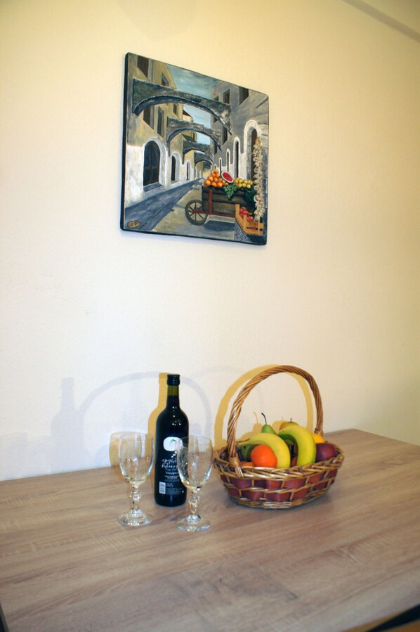 Une table avec une bouteille de vin, deux verres et un panier de fruits.