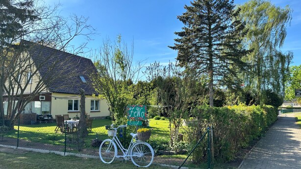 Una casa con techo de tejas, una bicicleta y un cartel que dice 'FeWo'.