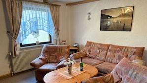 Una sala de estar acogedora con un sofá, una mesa de centro de madera y una ventana con cortinas.