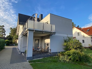 Ein modernes, zweistöckiges Haus mit Balkon, gepflasterter Auffahrt und einem gepflegten Garten.