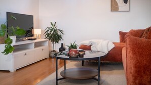 Una sala de estar moderna con una televisión de pantalla plana, una mesa de centro redonda, un sofá y una planta en maceta.