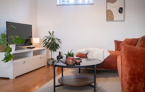 Un salon moderne avec un téléviseur à écran plat, une table basse ronde, un canapé et une plante en pot.