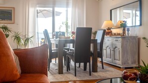Una sala de estar con sofá, un comedor con mesa y sillas, un armario y una ventana con cortinas.