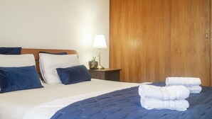 Una cama bien hecha con almohadas, una lámpara de noche y un armario de madera en una habitación de hotel.