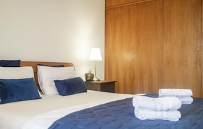 Un lit bien fait, avec des oreillers, une lampe de chevet et une armoire en bois, dans une chambre d’hôtel.