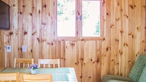 Une pièce en bois avec une fenêtre, une table entourée de chaises, un téléviseur et un canapé.
