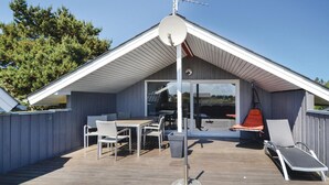 Een overdekt buitengebied met een tafel en stoelen, een hangstoel en een schotelantenne.
