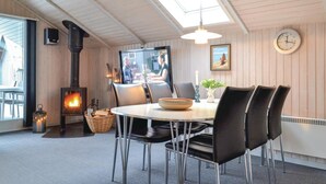 Een gezellig eetgedeelte met een ronde tafel, zwarte stoelen, een open haard, een televisie en een klok aan de muur.