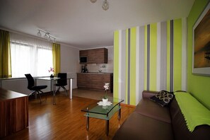 Un salon moderne avec une table basse en verre, un canapé marron et un coin repas comprenant une petite table et des chaises.