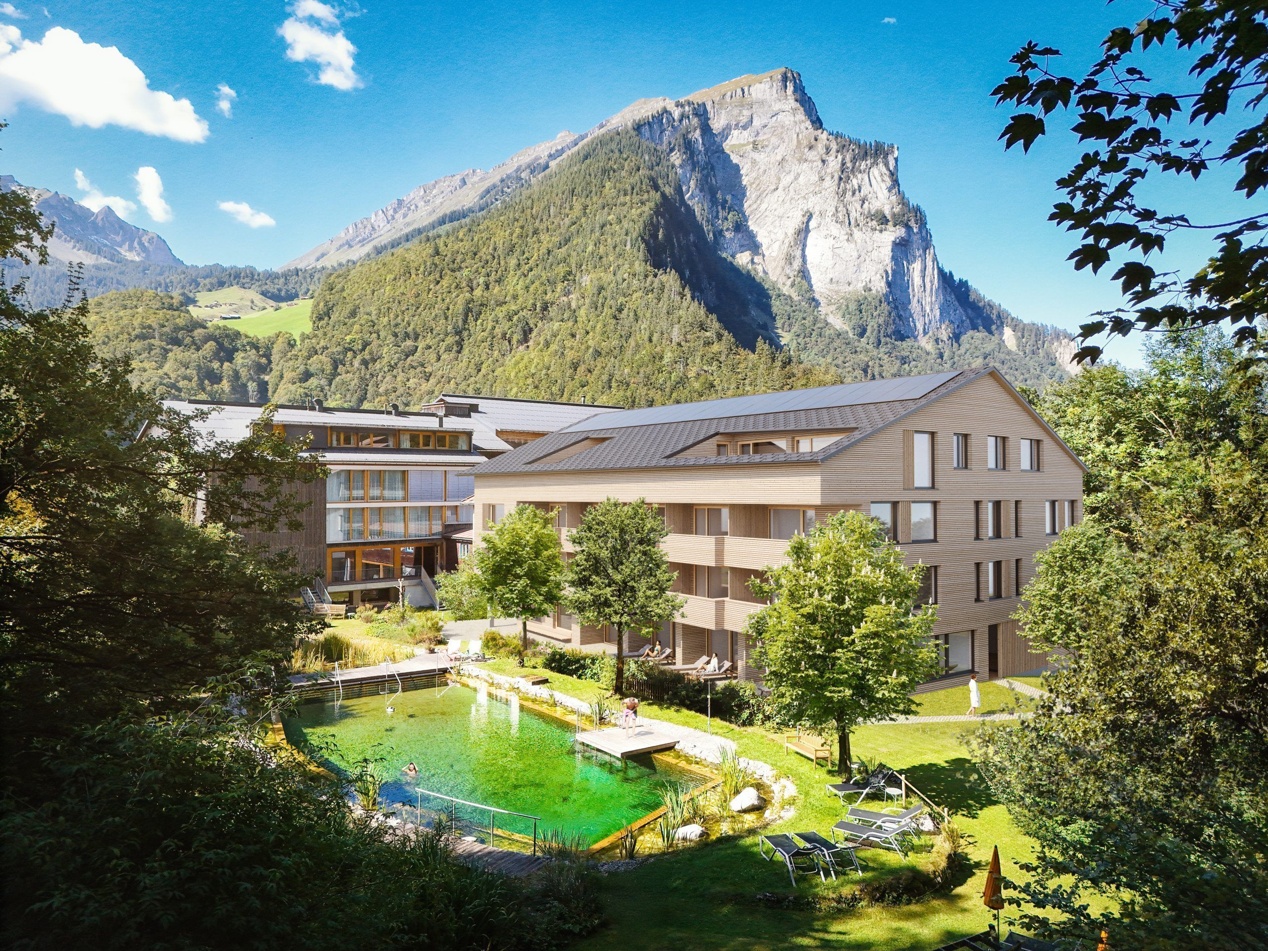Un hotel moderno con piscina, immerso nel verde e circondato da montagne.