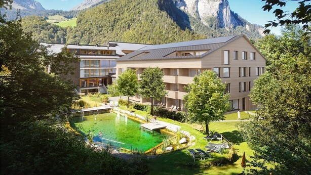 Un hotel moderno con piscina, rodeado de exuberante vegetación y montañas.