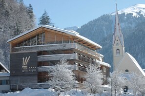 A hotel with a wooden facade, a bell tower, and snow-covered surroundings.