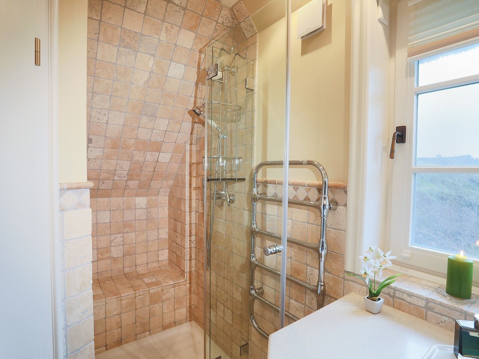 A bathroom with a glass-enclosed shower, a towel rack, and a window with a view.