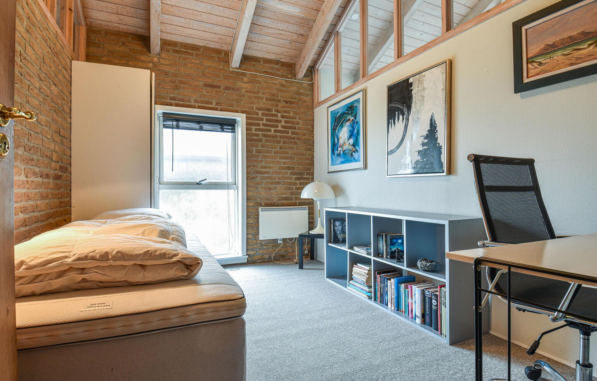 A bedroom with a bed, a desk, a chair, a bookshelf, and a window.