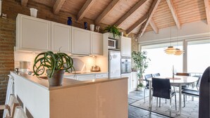 A modern kitchen with white cabinets, a central island, and a dining area with a table and chairs.