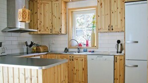 Une cuisine avec des meubles en bois, un évier en acier inoxydable, un lave-vaisselle et un réfrigérateur.