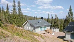 Une maison à deux étages avec un toit en pente, une terrasse à l’avant et un garage.