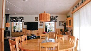 Un coin repas en bois avec une table ronde et des chaises, un luminaire suspendu et un téléviseur fixé au mur.