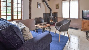 Un salon confortable avec une cheminée, un canapé, un fauteuil et un téléviseur.
