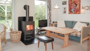 A cozy living room with a wood-burning stove, a TV, a sofa, and a dining table. - 2 bedroom nice home in Hejls (Hejls)