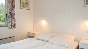 A bedroom with a bed, a nightstand, a lamp, a window with curtains, and a painting on the wall. - 2 bedroom nice home in Hejls (Hejls)