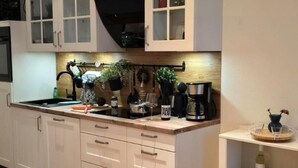 A modern kitchen with white cabinetry, a wooden countertop, and various appliances.