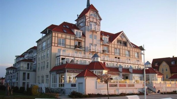 A multi-story hotel with a traditional architectural style, featuring balconies and a central tower.