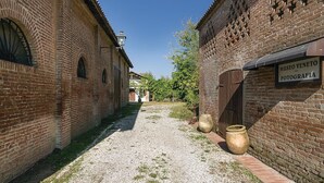 Une ruelle étroite bordée d’immeubles en briques, une enseigne indiquant le « Museo Veneto della Fotografia », et de grands pots disposés sur le sol.