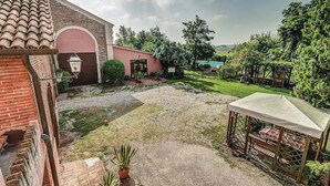 Une cour avec un bâtiment en briques, un petit jardin et une pergola.