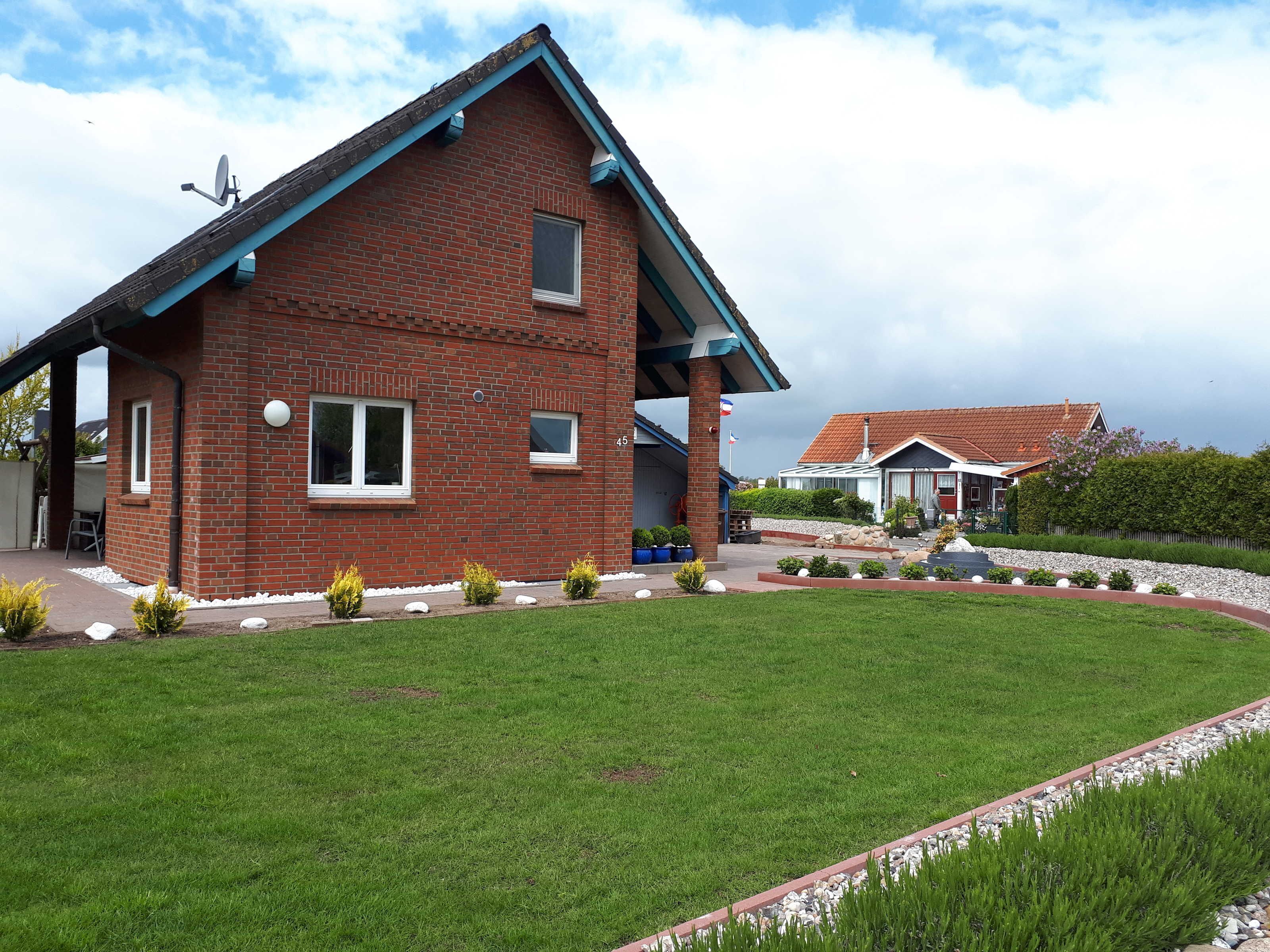 A two-story brick house with a sloped roof, a covered porch, and a well-maintained lawn.