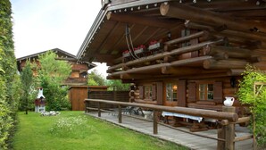 Eine rustikale Holzhütte mit einer Holzdiele, einem Kamin aus Stein und einem kleinen Garten.