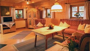 Ein gemütliches Holzhaus-Interieur mit einer Couch, einem Tisch und einem Fernseher.