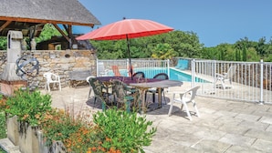 A patio with a pool, stone walls, and outdoor furniture.