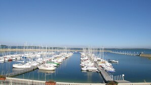 Een jachthaven met tal van boten die in rijen liggen, een heldere lucht en rustig water.