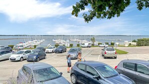 Een parkeerplaats met auto's en een jachthaven op de achtergrond.