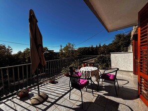 Eine Terrassengruppe mit Tisch und Stühlen, ein kleiner runder Tisch und ein Blumentopf.