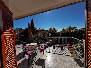 A balcony with a tiled floor, two chairs with cushions, a small round table, and potted plants. - Holiday Apartment with Balcony and View (Crikvenica)