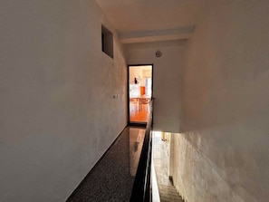 Um corredor estreito com piso de azulejos que leva a um quarto com mesa e cadeiras de jantar.