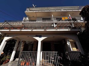 Ein mehrstöckiges Gebäude mit Balkonen, ein Schild, das es als Apartment ausweist, und ein klarer Himmel.