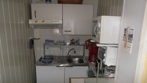Een kleine keuken met een magnetron, spoelbak en koffiezetapparaat.