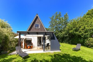 Een modern huis met een terras, tuinmeubilair en een tuin.